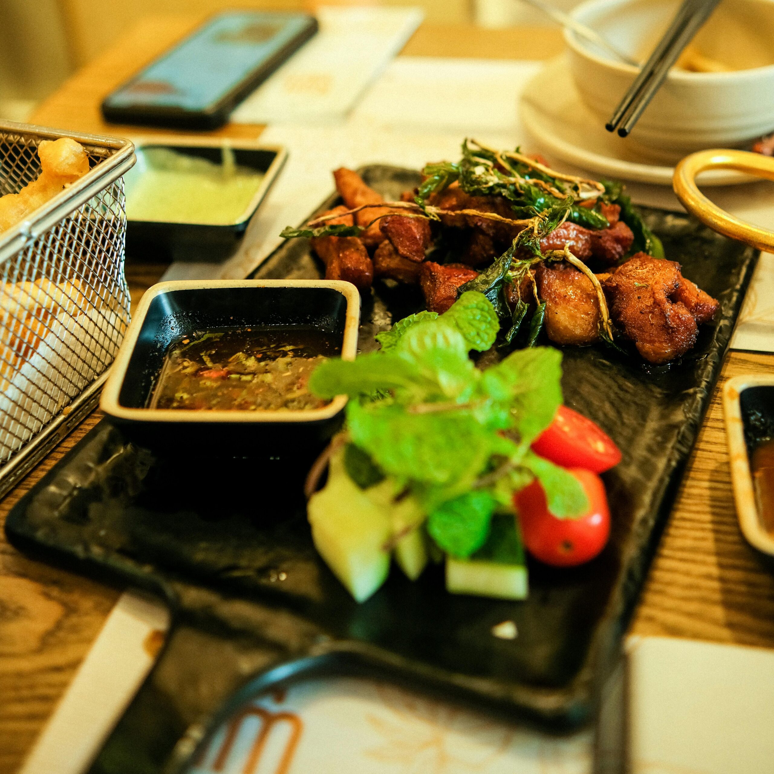 Close-up of a delicious Asian meal with fresh vegetables and dipping sauce on a tray.