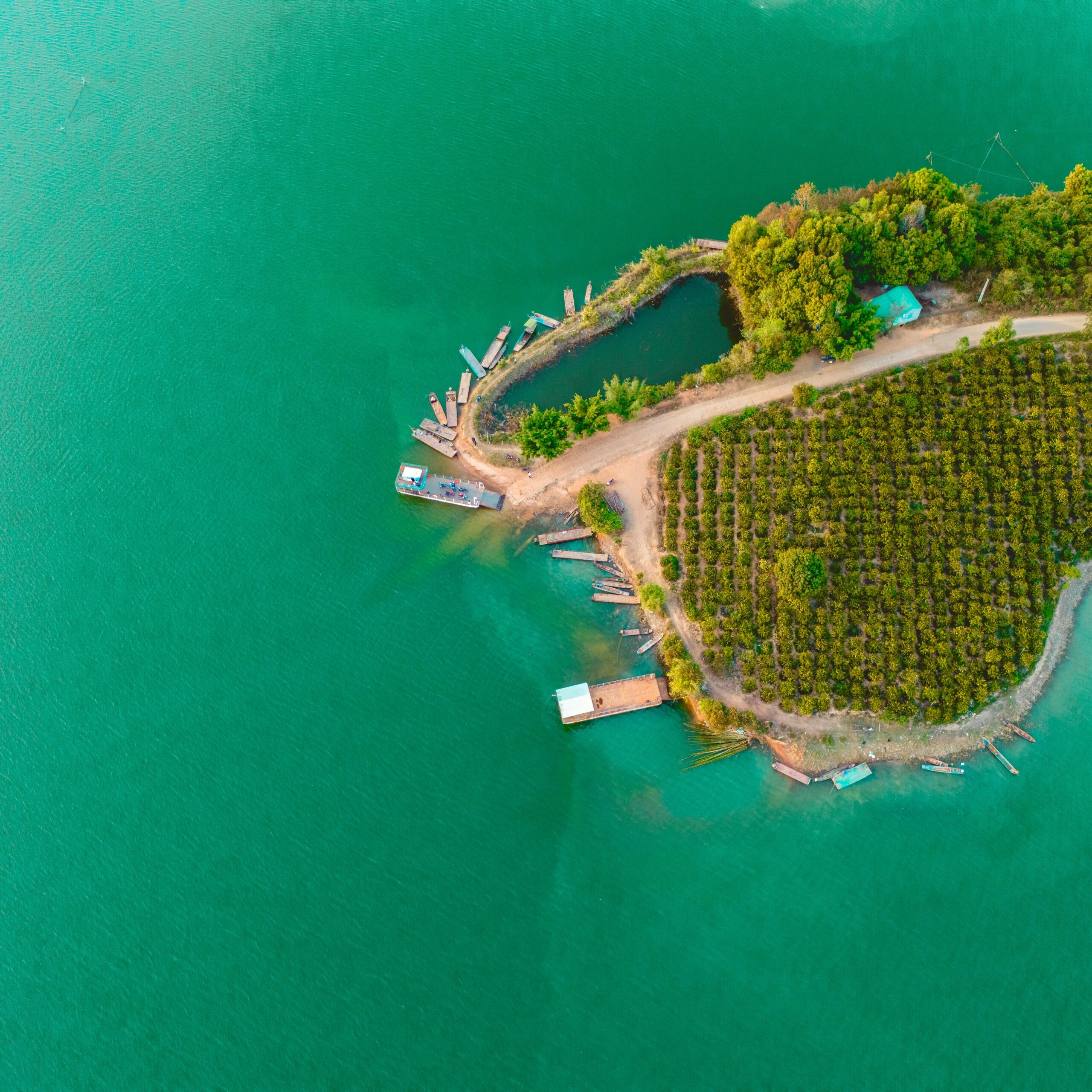 Aerial shot of a small island with green vegetation surrounded by vibrant turquoise water, perfect for travel inspiration.