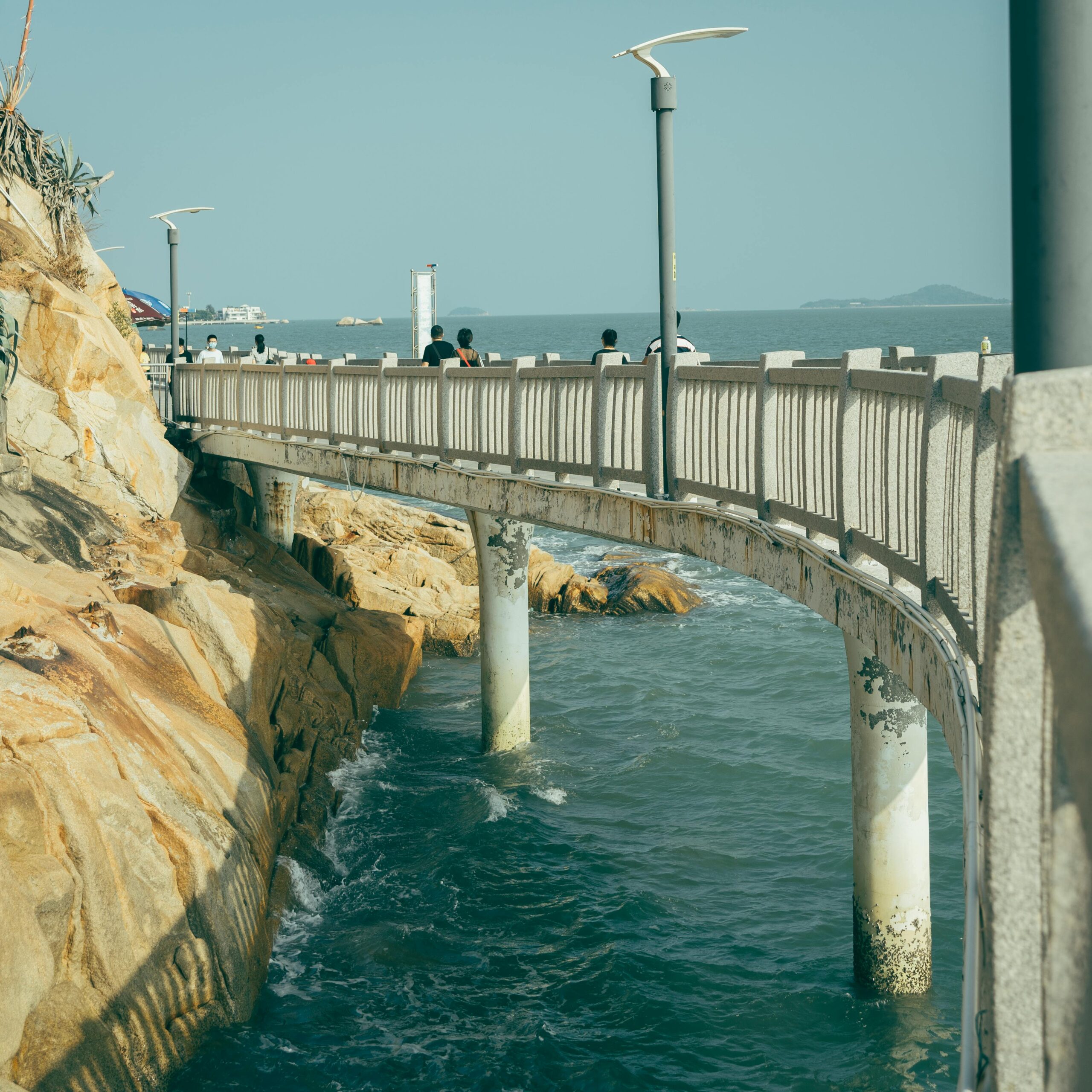 People strolling on an elevated coastal walkway, offering stunning ocean views.