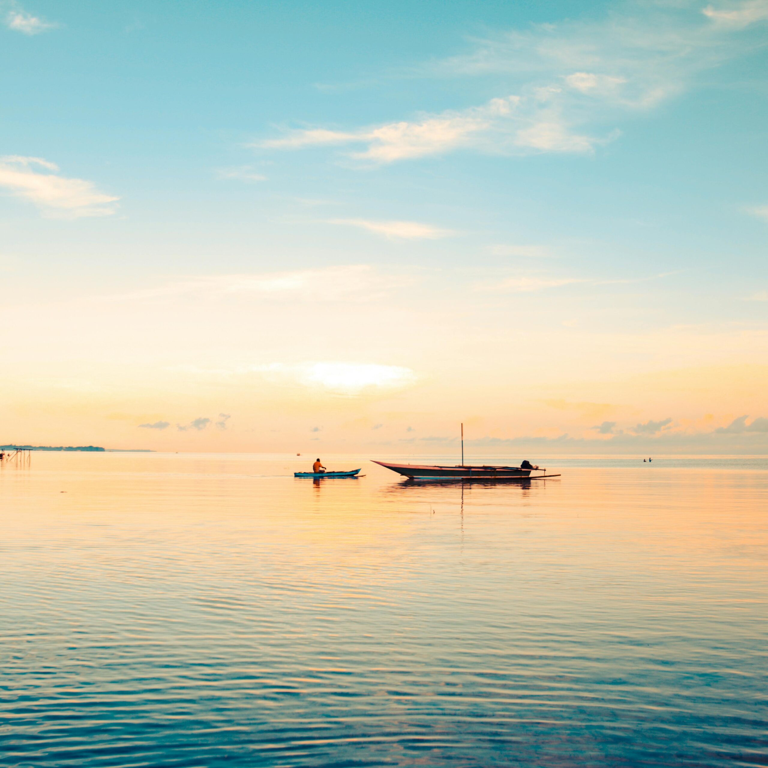 A fisherman on a boat at sunrise in serene waters off Papua, Indonesia, capturing peace and tranquility.