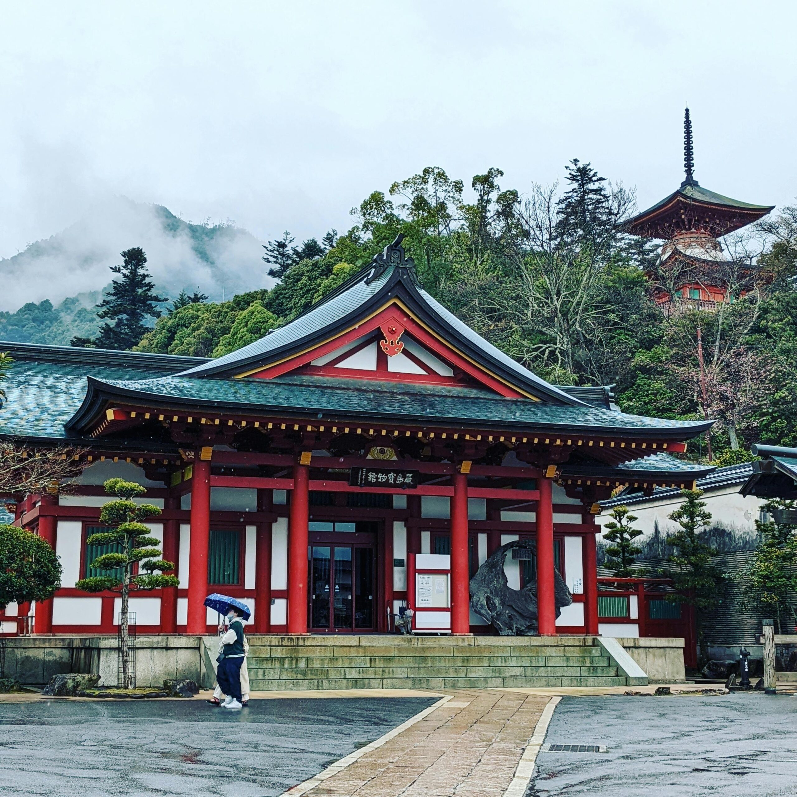 Beautiful Shinto shrine with pagoda amidst misty forest, showcasing traditional Japanese architecture and spirituality.