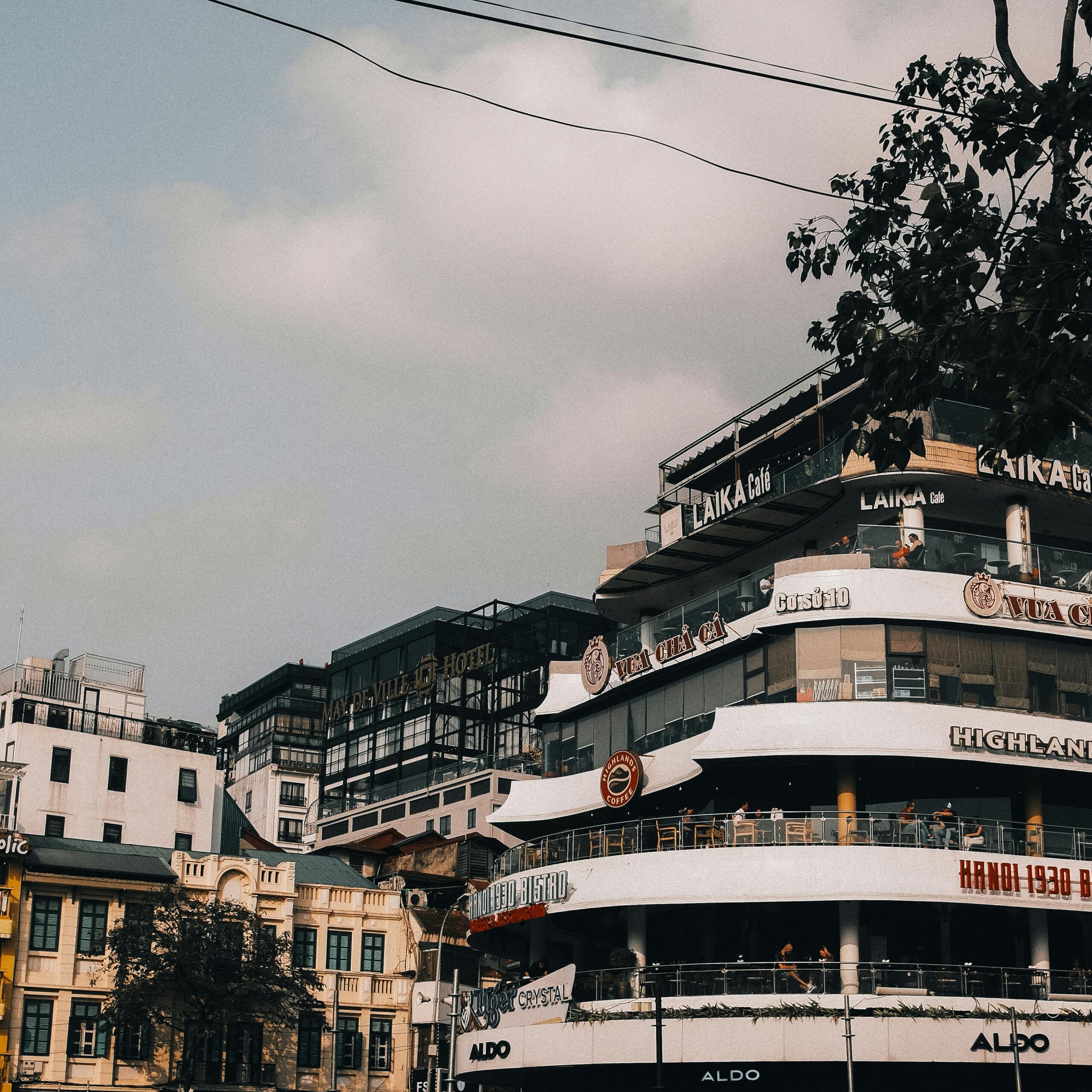 Lively street view of a multi-story building in Hanoi, capturing the city's bustling atmosphere.