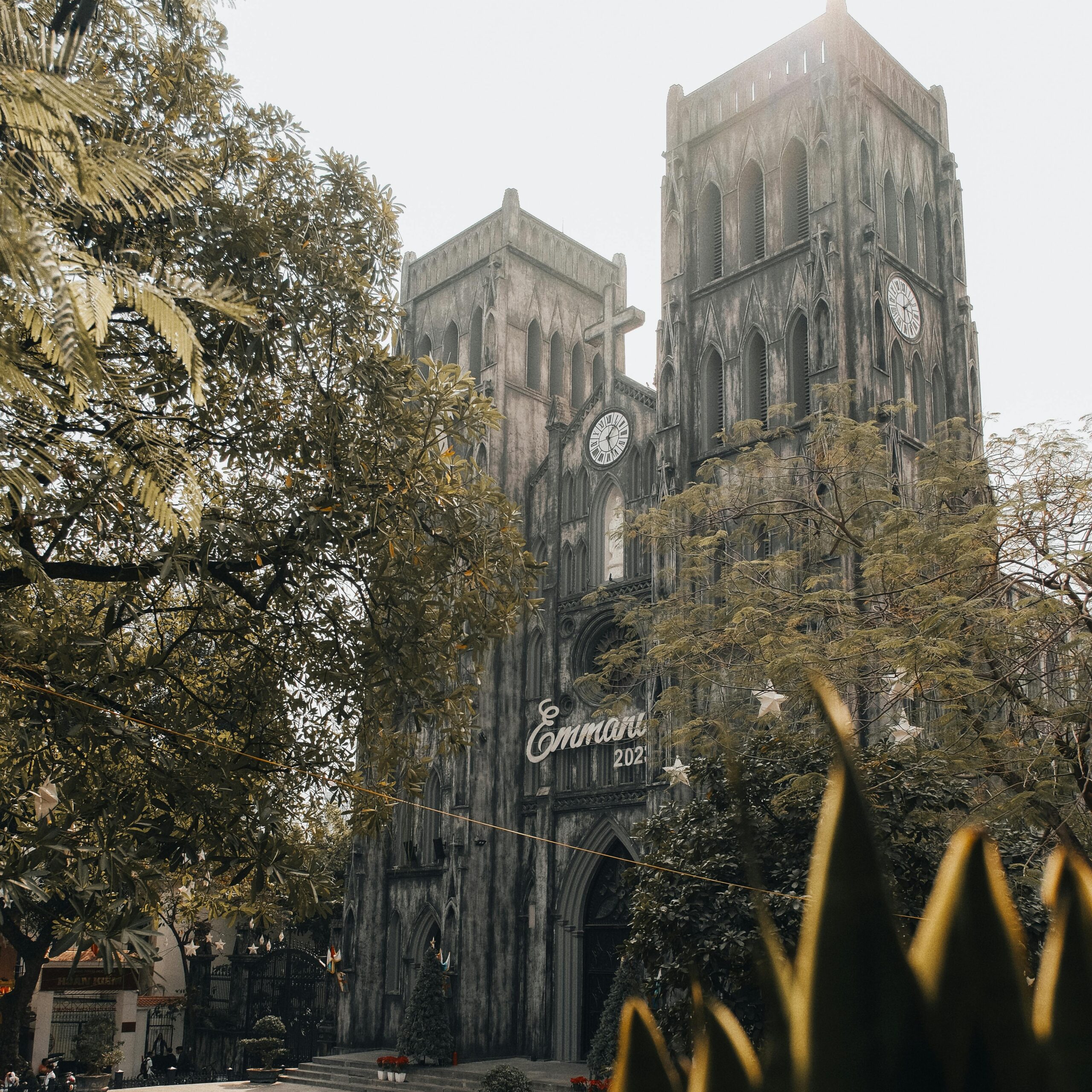 Gothic-style St. Joseph's Cathedral in Hà Nội surrounded by lush greenery on a sunny day.
