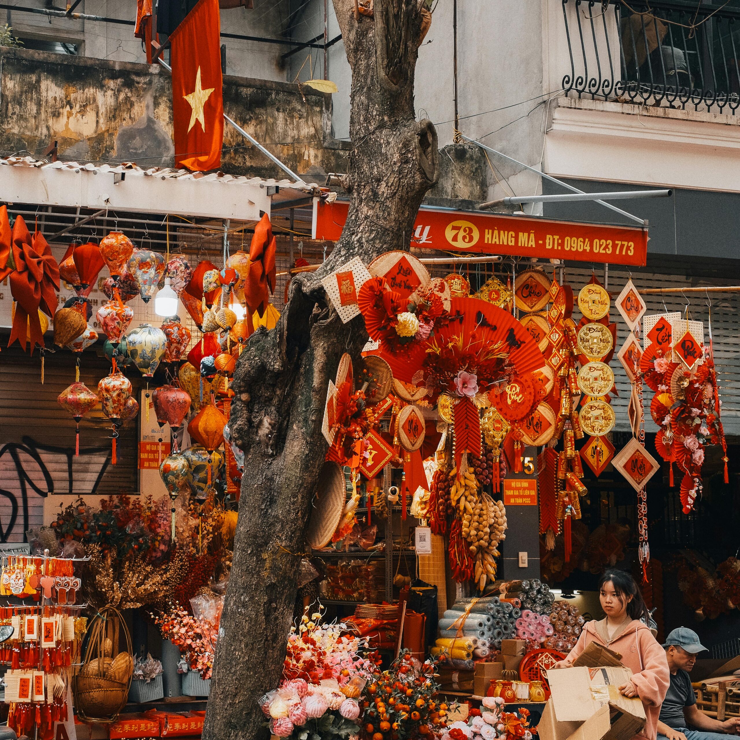 Vibrant festive decorations at a street market in Hanoi, Vietnam, showcasing traditional lanterns and flowers.
