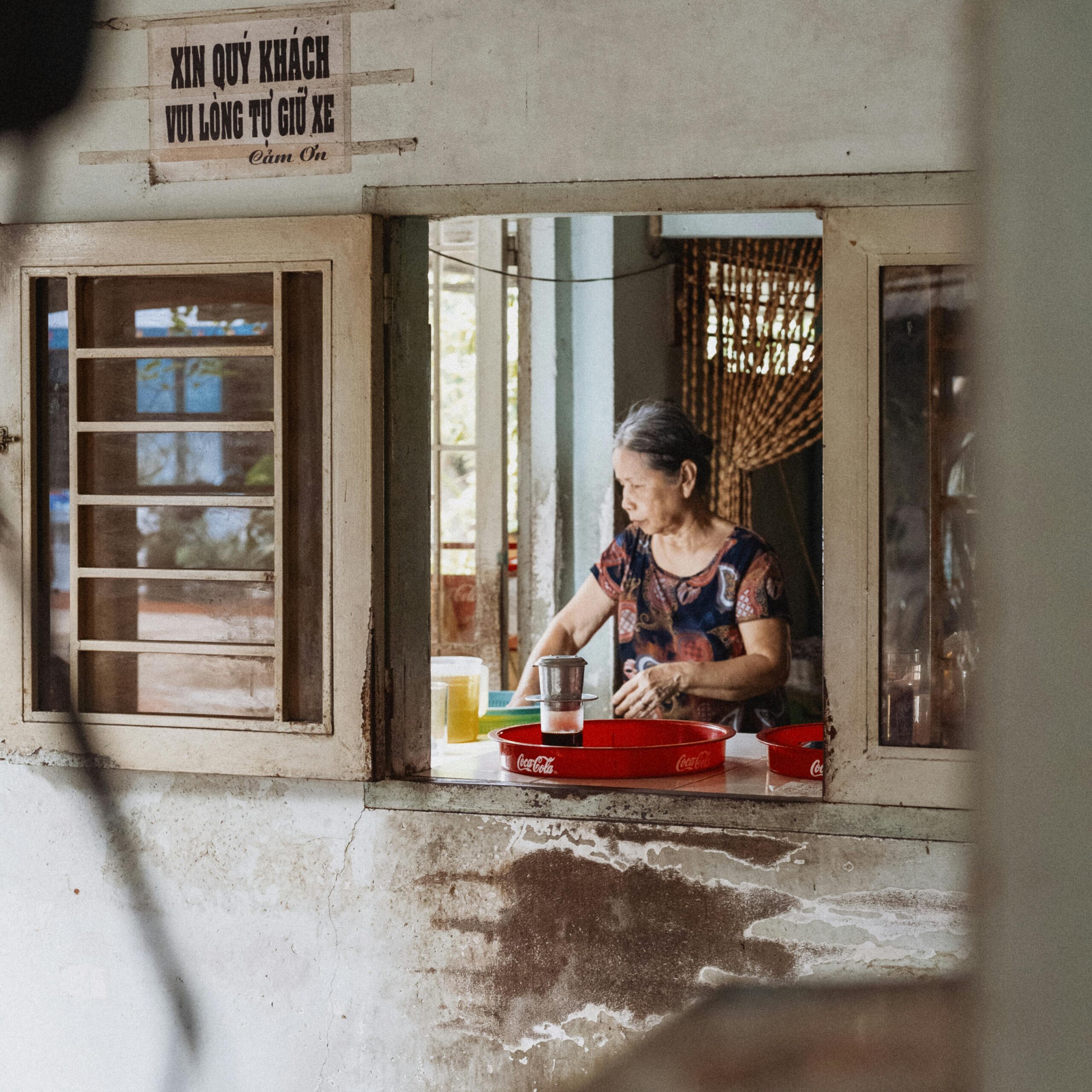 A senior woman prepares a drink inside a rustic cafe, creating a warm and homely atmosphere.