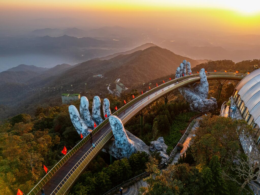 Aerial view of the iconic Hand Bridge in Ba Na Hills, Vietnam during a vibrant sunset.